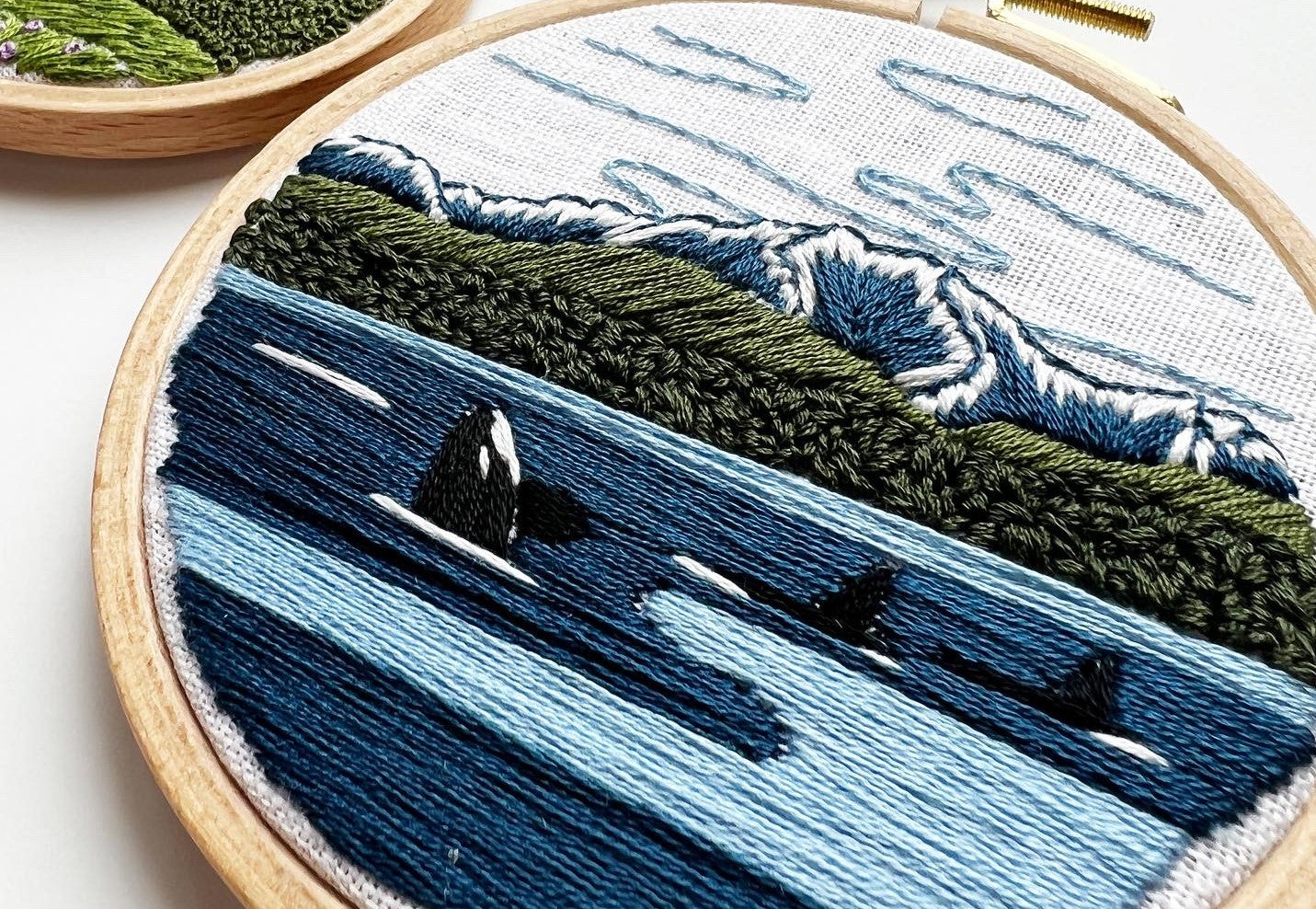 Orcas in the Sound Hand Embroidery PDF.  File includes pattern for transfer and booklet with easy to follow step by step instructions.  Part of the Pacific Wanderlust Collection.  Three Orcas swimming with Mountains in the background.
