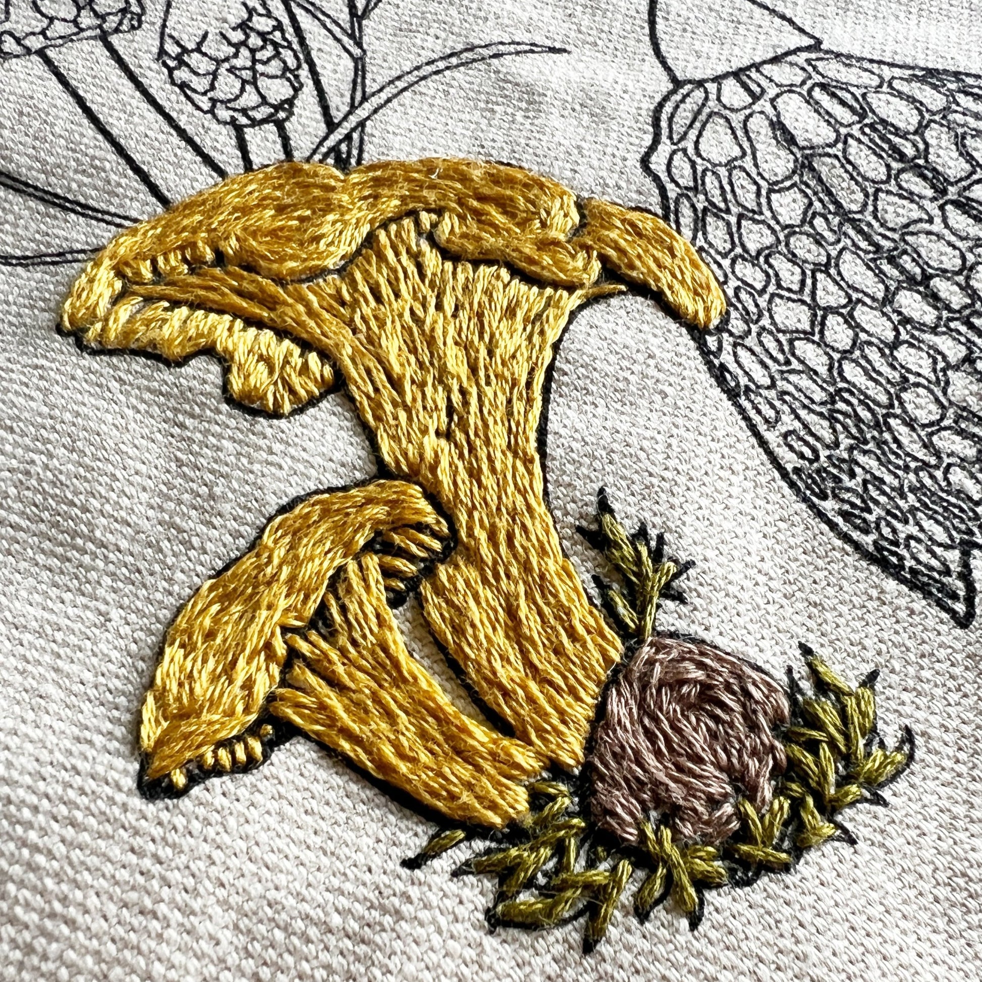 Close up of stitching on chanterelle mushroom.  A yellow gold floss has been used to show detail of cap and stem.