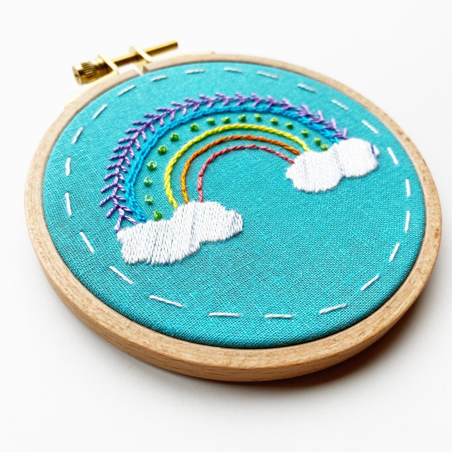 Beginner Embroidery kit of Rainbow.  Shows Rainbow on teal background.  Teaches beginner stitches for embroidery.