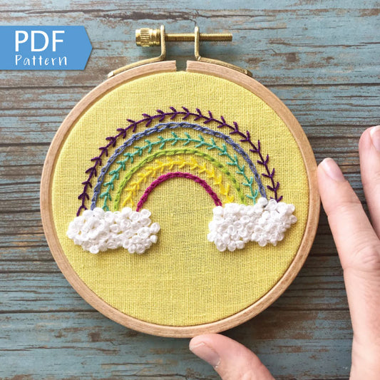 Radiant Rainbow PDF.  This pattern teaches different stitches resulting in a modern rainbow with puffy clouds below a 6 banded rainbow.