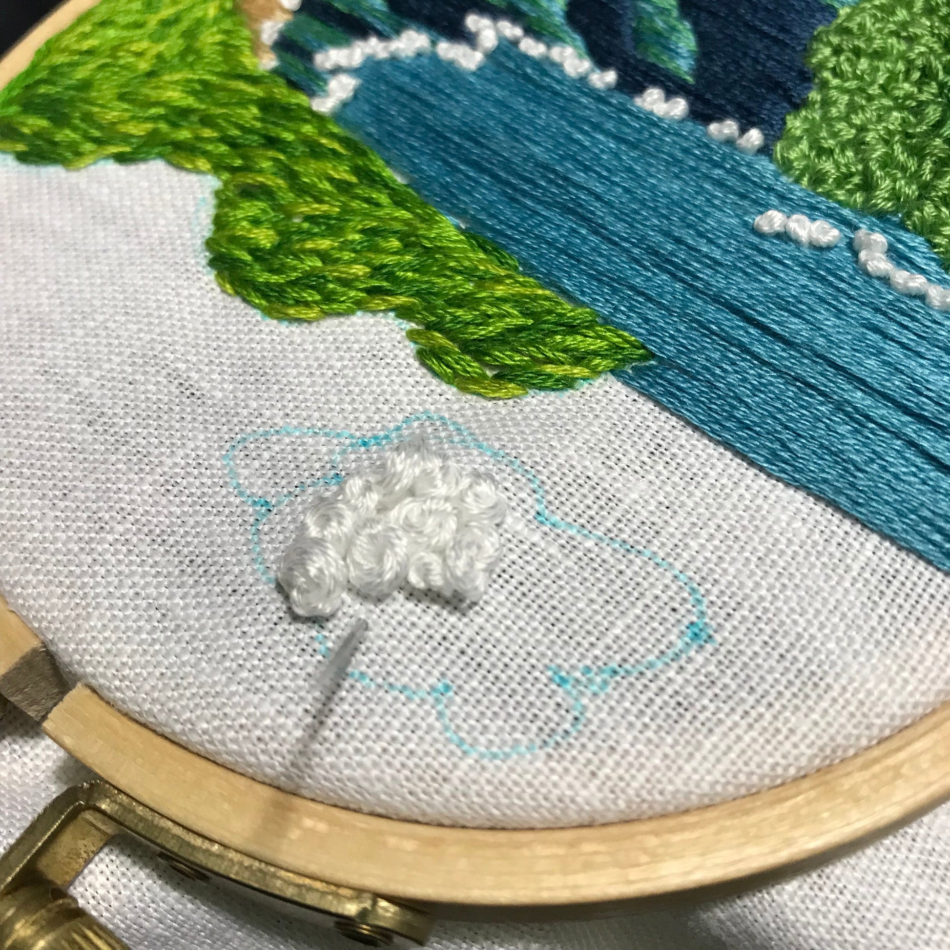 Close up stitch details of cloud with white knots.  Cloud is outlined in blue water soluble marker.