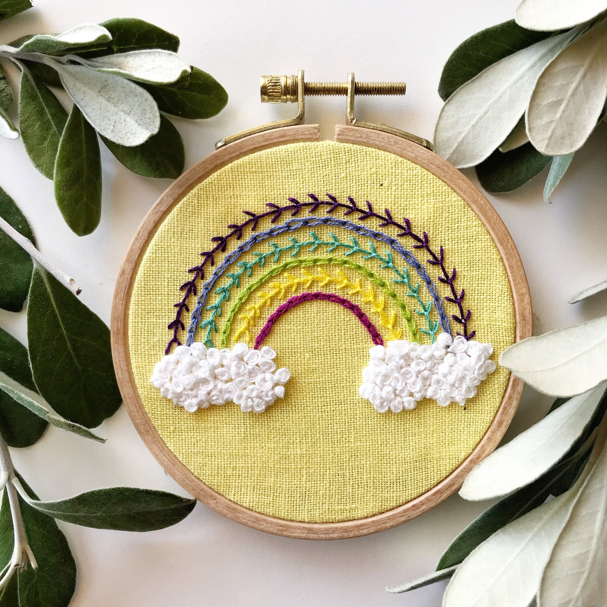 Radiant Rainbow PDF.  This pattern teaches different stitches resulting in a modern rainbow with puffy clouds below a 6 banded rainbow.