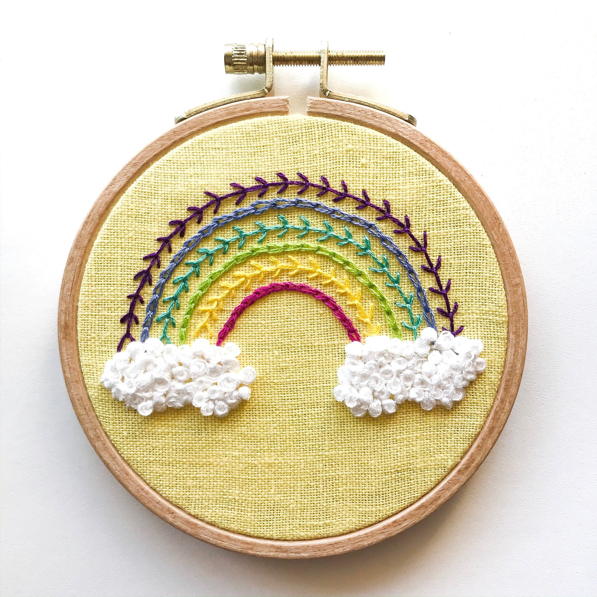 Radiant Rainbow PDF.  This pattern teaches different stitches resulting in a modern rainbow with puffy clouds below a 6 banded rainbow.