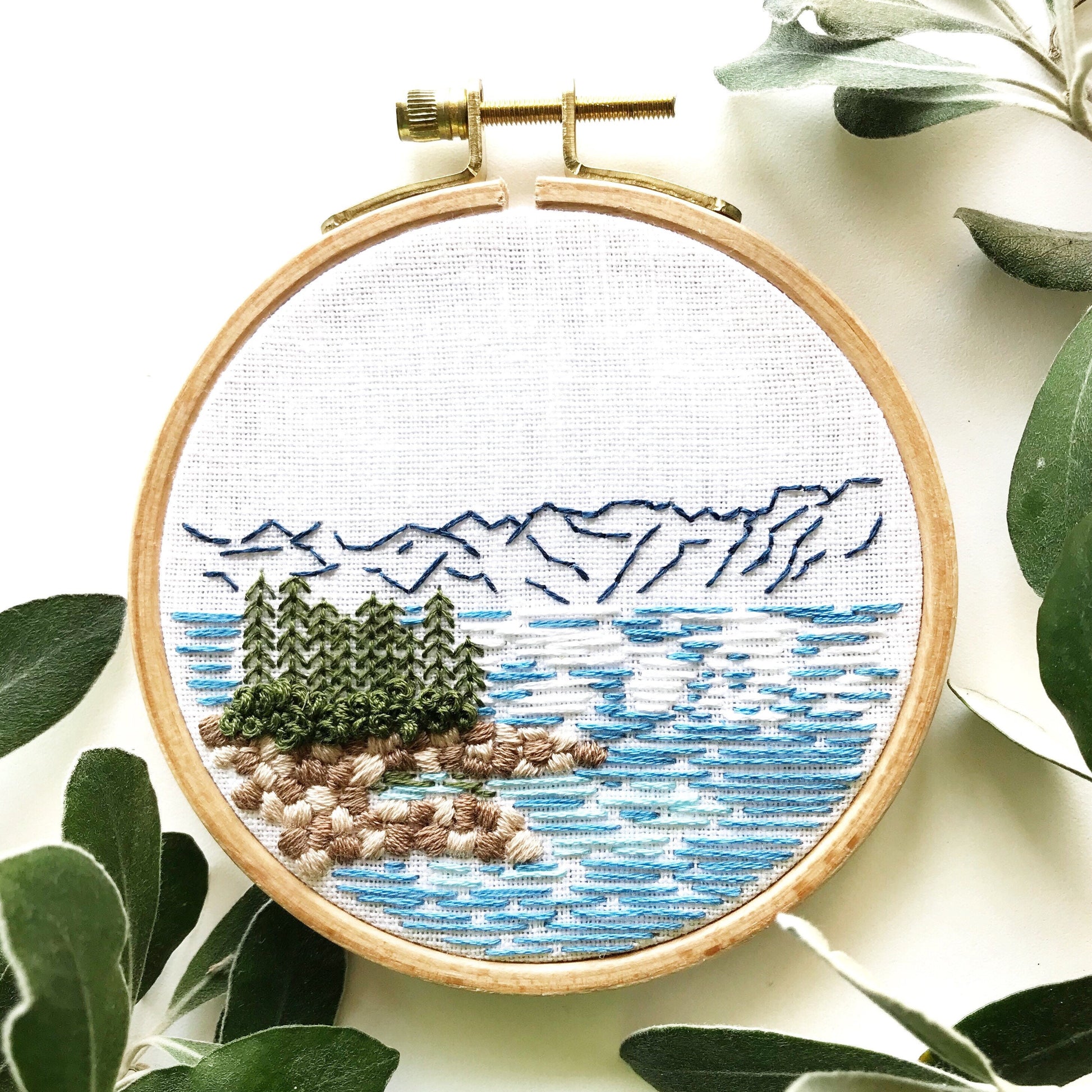 Lake Tahoe is a great pattern to DIY your own modern embroidery hoop art. This 12 page pdf details everything you need to know to stitch this beautiful embroidery.  Mountains in the background with trees, rocks and lake in front.
