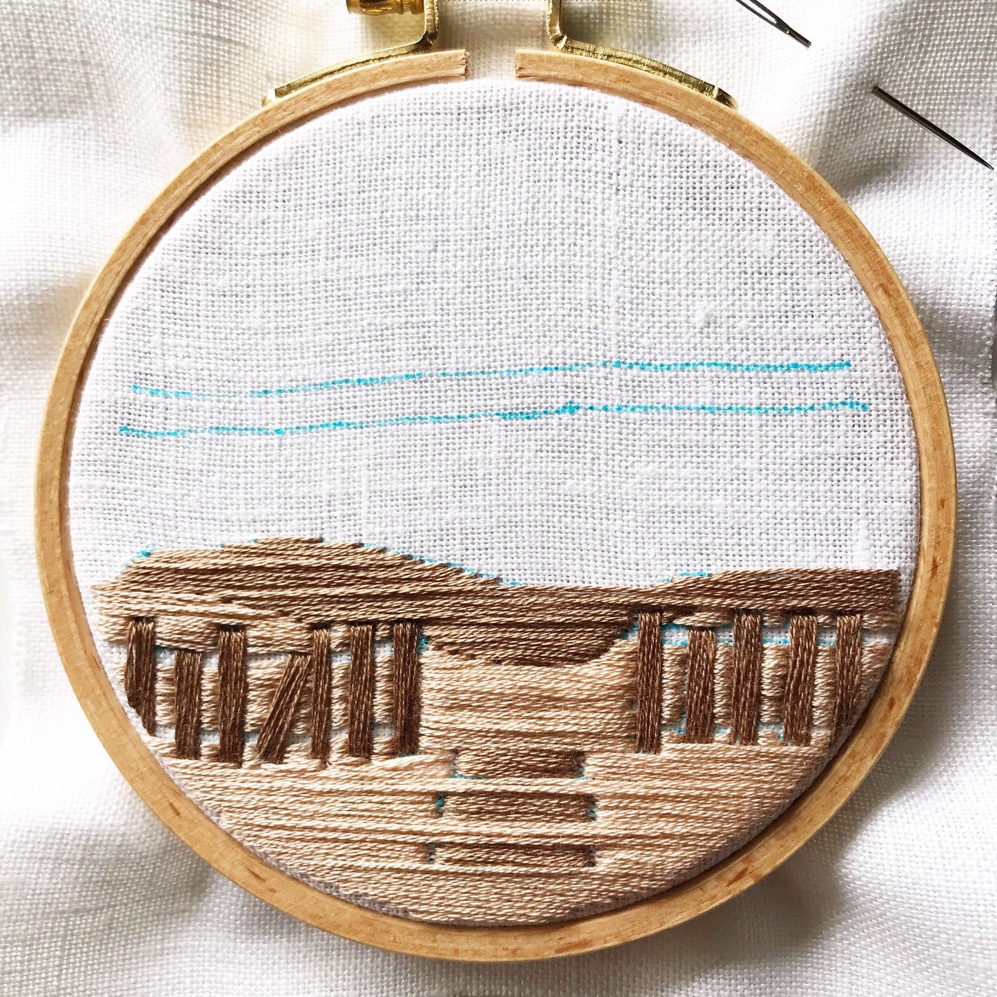 Close up of A Day at the Beach Modern Embroidery. Long stitches in shades of brown are complete awaiting definition. Blue marker denotes next stitches.