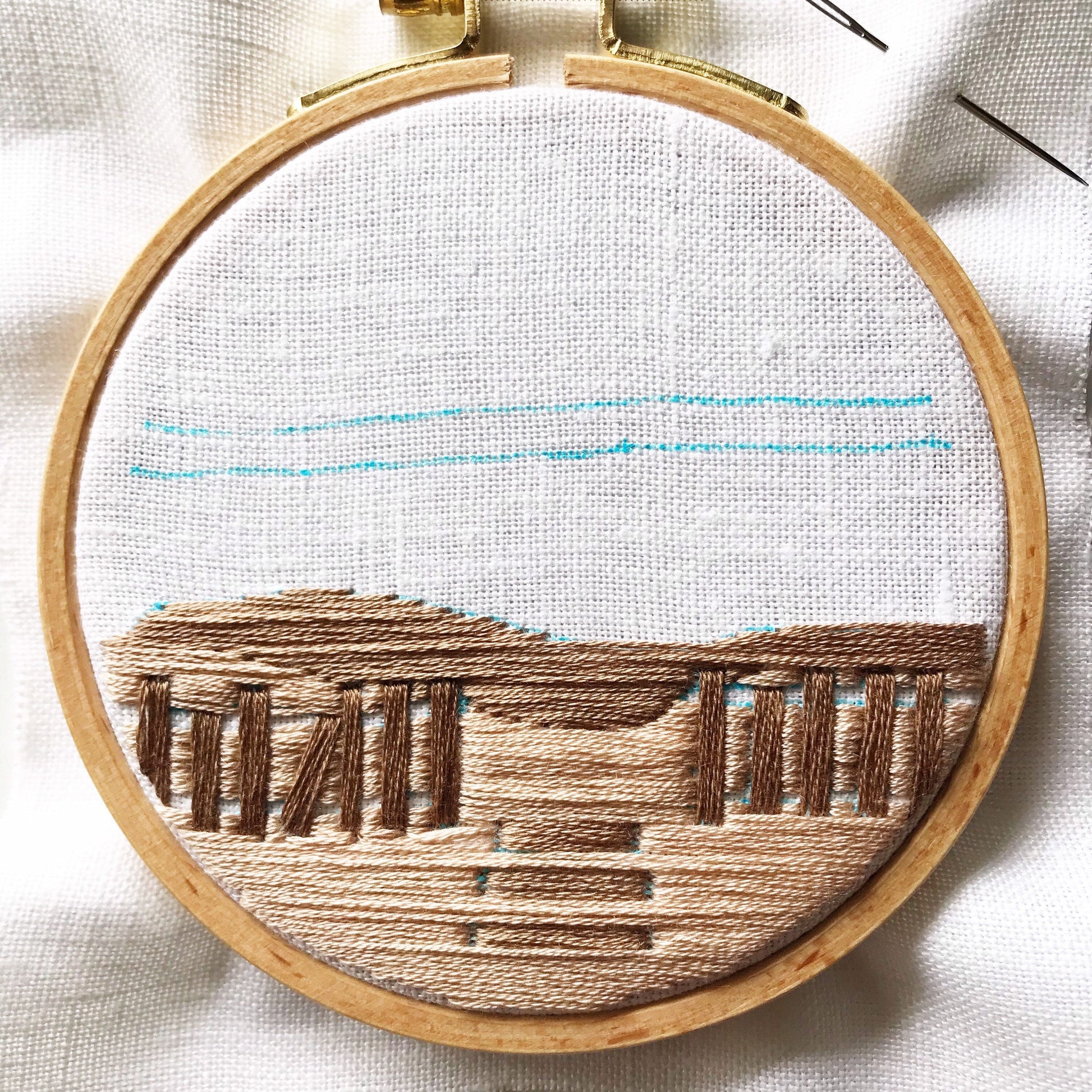 Close up of A Day at the Beach Modern Embroidery.  Long stitches in shades of brown are complete awaiting definition.  Blue marker denotes next stitches.