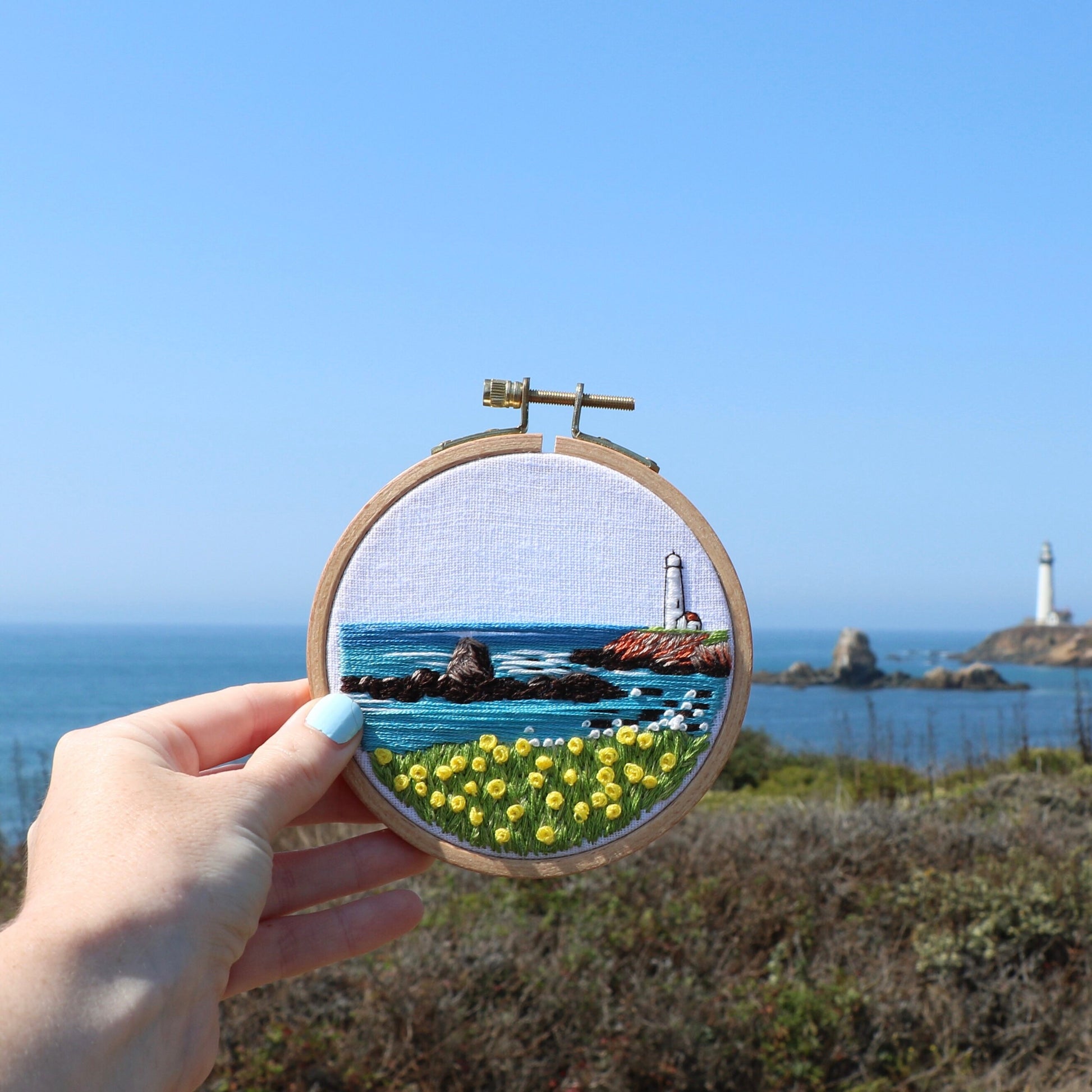 Completed Lighthouse by the Bay Beginner Embroidery hoop held in front of Pigeon Point Lighthouse.