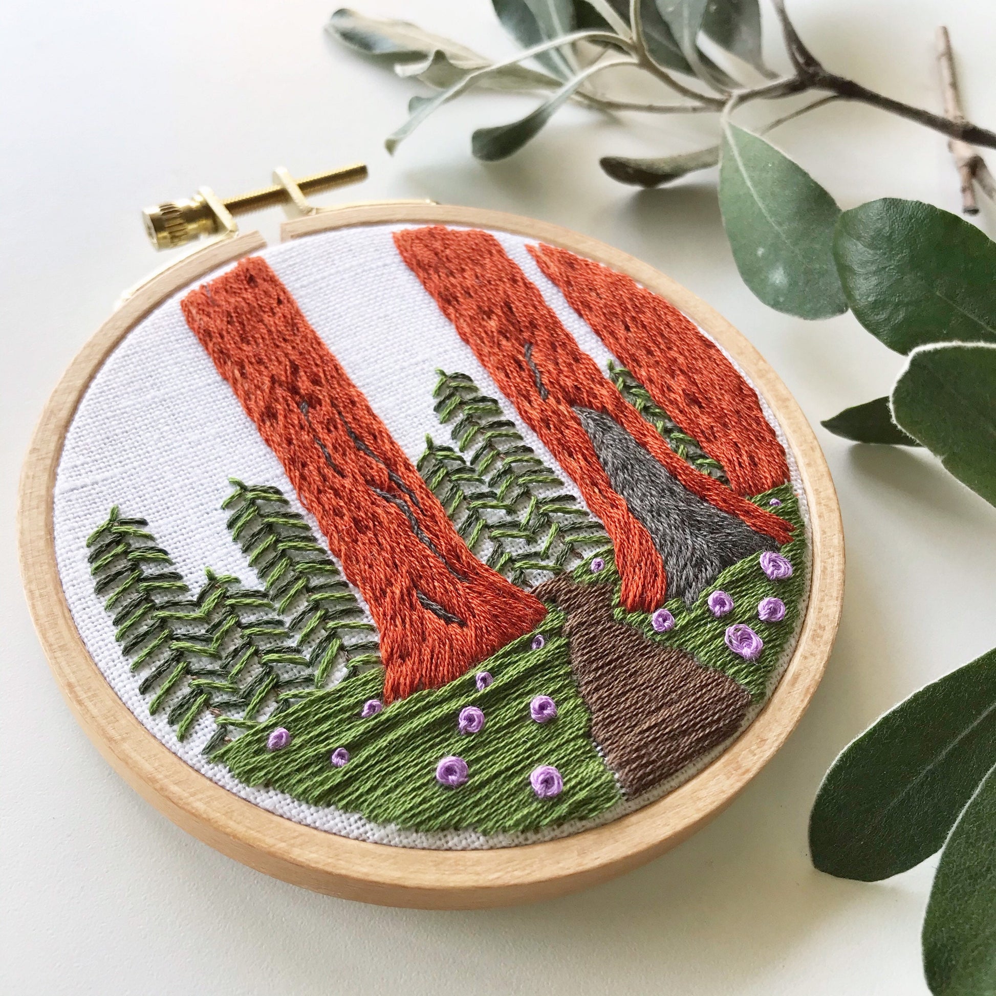 Sequoia Grove PDF. Three tall Sequoias rise from the base of the embroidery with a small trail between them. PDF includes pattern for image transfer and 11 page booklet with easy to follow directions.