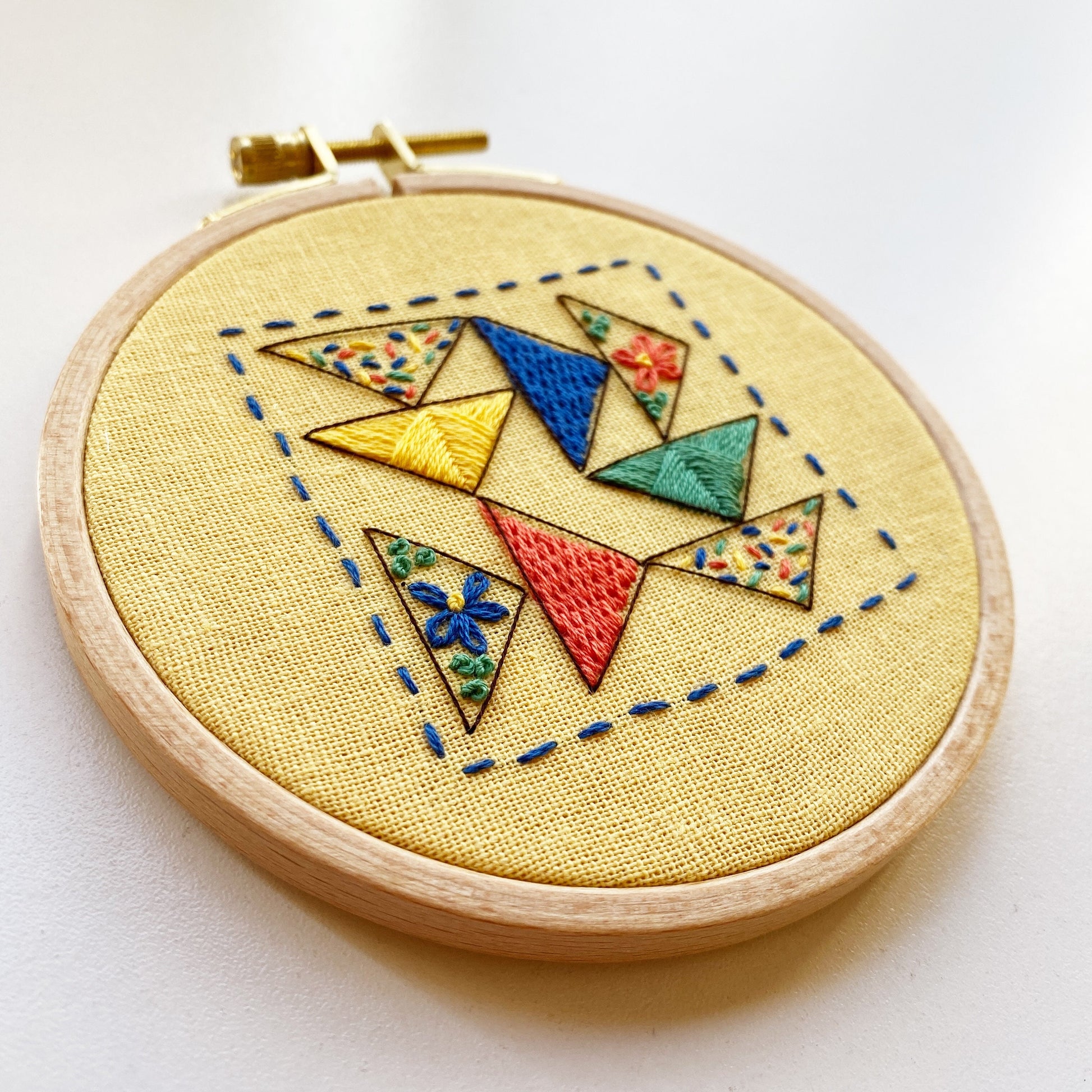 Rosanna Diggs Embroidery Triangle Tango PDF.  Design features a modern take on the traditional flying geese quit pattern.  Learn new stitches while making something beautiful. PDF includes pattern and 12 pages of easy to follow directions.
