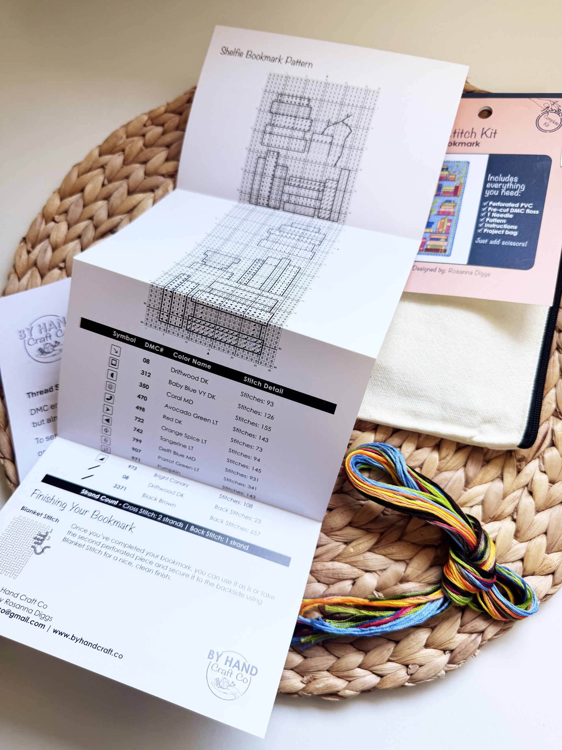 A handmade embroidery thread kit displayed on a woven straw mat, featuring a bookmark pattern booklet, colorful embroidery floss.