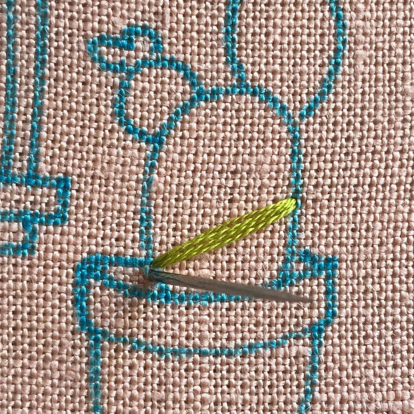 Cozy Cactus Kit in progress.  Green embroidery floss on pink linen with blue marker showing design.
